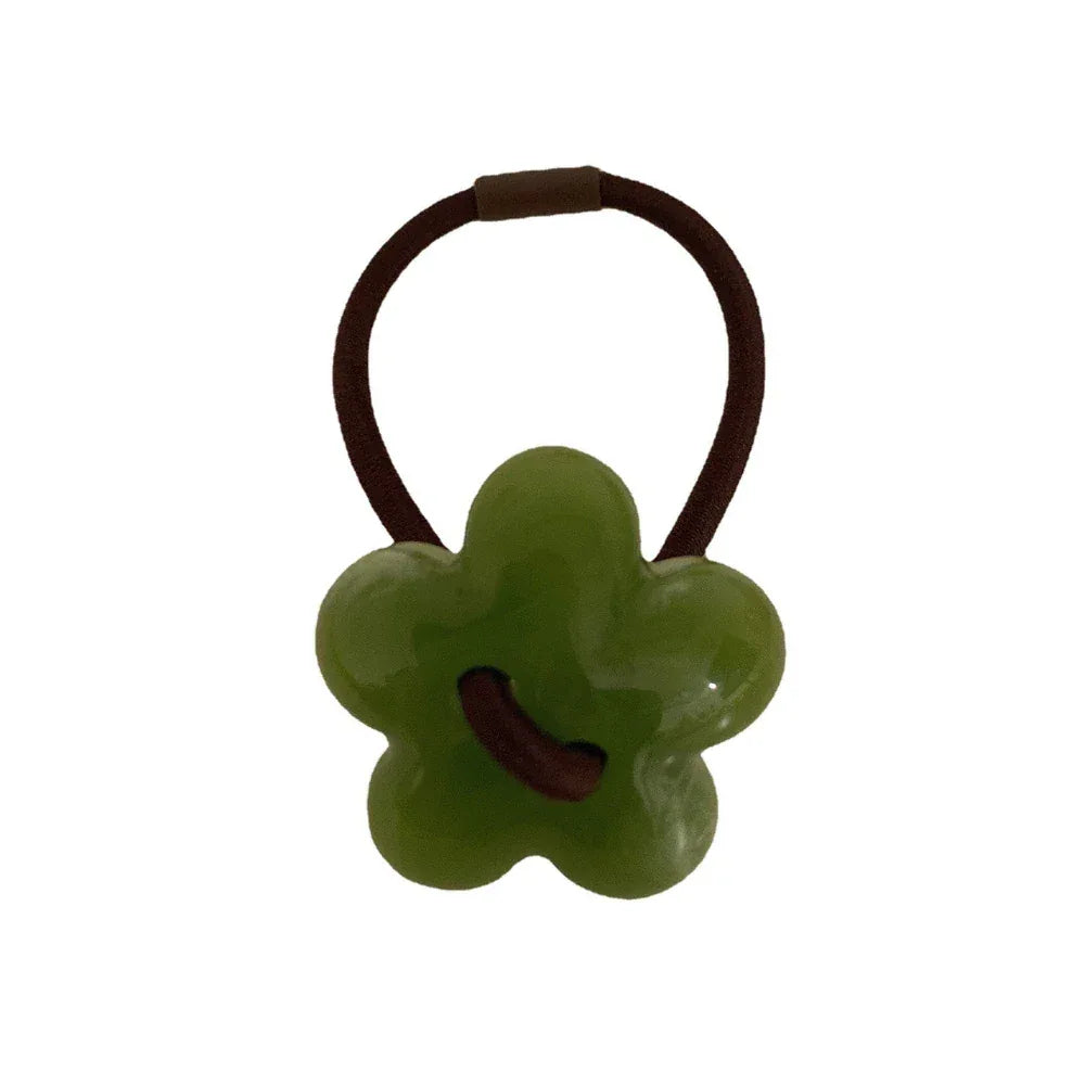 A single green flower-shaped hair tie with a brown elastic band. Main image