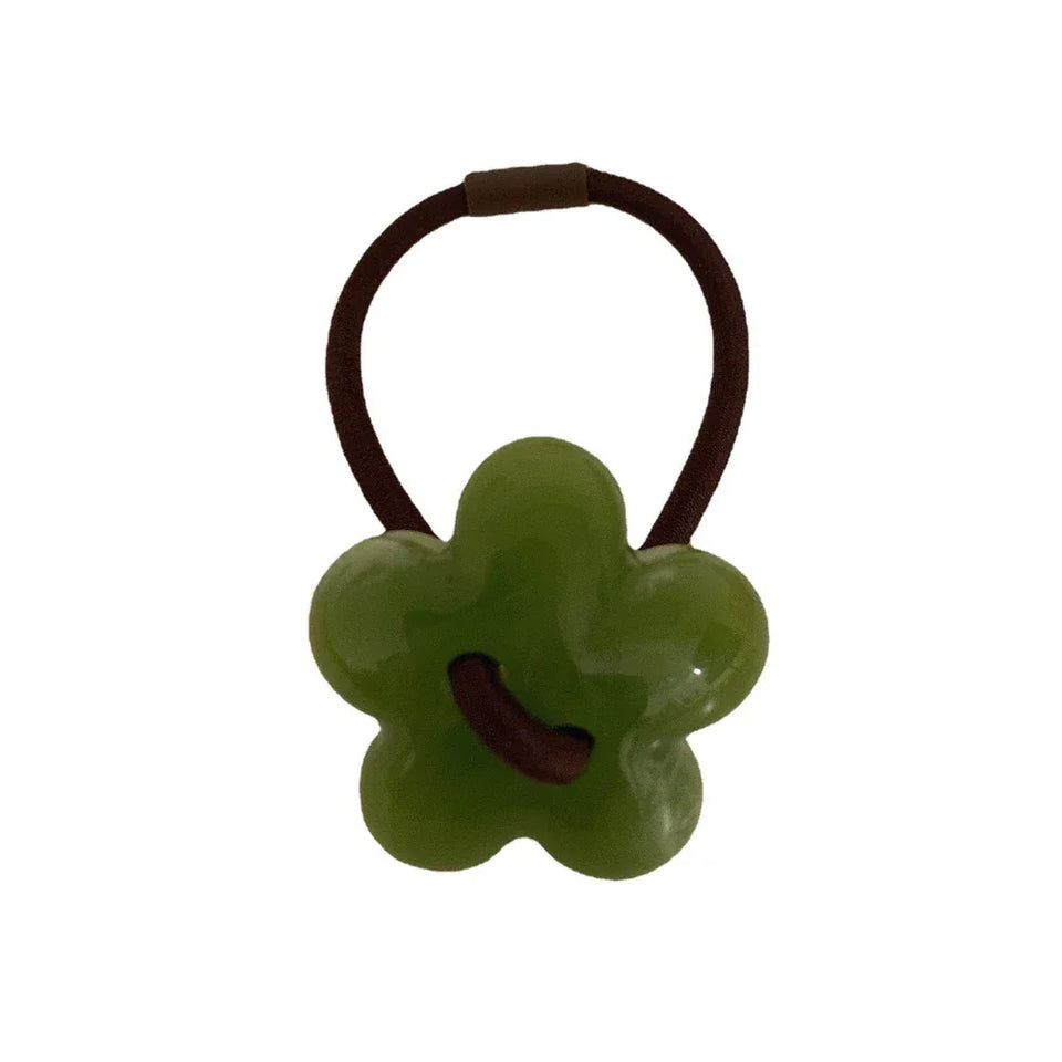 A single green flower-shaped hair tie with a brown elastic band. Main image