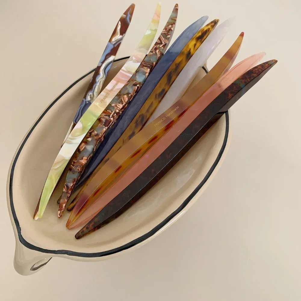 collection of curved marbled acetate hair pins arranged in a decorative bowl
