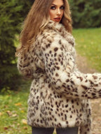 Woman from behind wearing a spotted faux fur coat and grey jeans, with long blonde hair, standing outdoors.