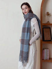 Woman wearing a blue and brown plaid scarf with fringe detail over a white top