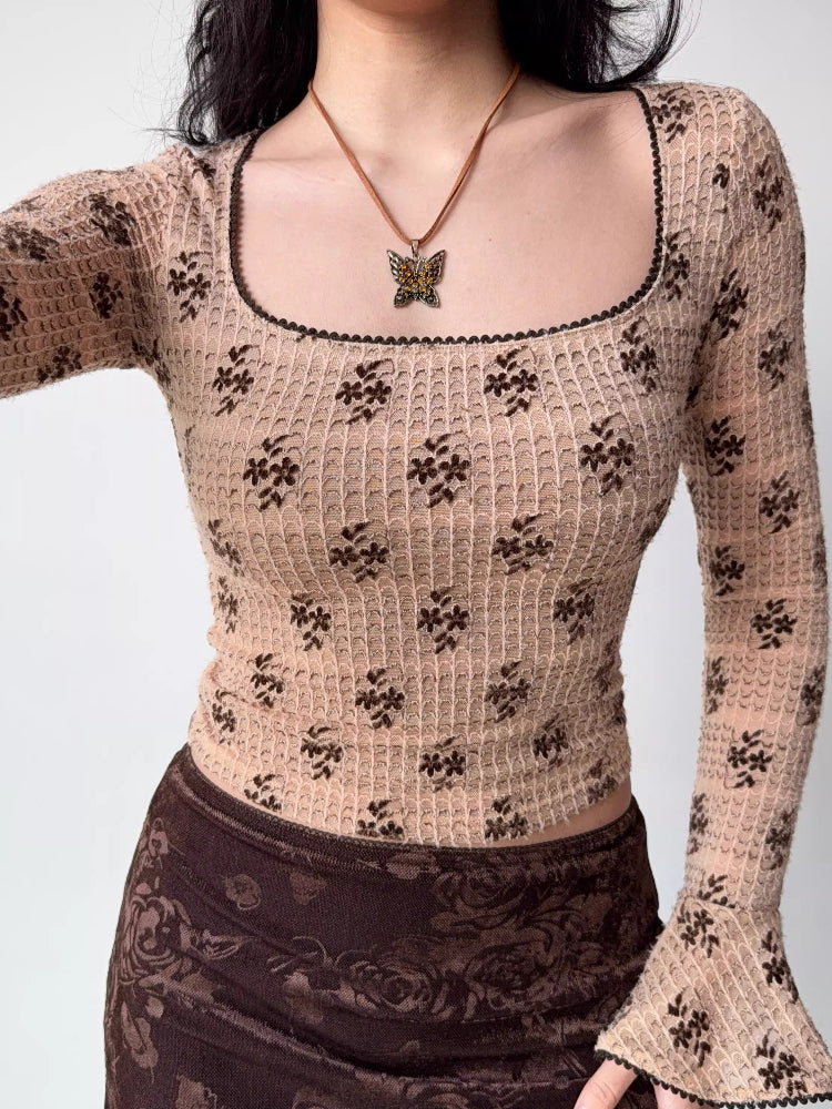 Front view of a fitted, long-sleeved square neck top with an allover brown floral print on a beige textured knit fabric. The neckline and sleeve cuffs have dark scalloped trim.
