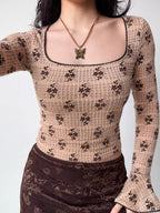 Front view of a fitted, long-sleeved square neck top with an allover brown floral print on a beige textured knit fabric. The neckline and sleeve cuffs have dark scalloped trim.