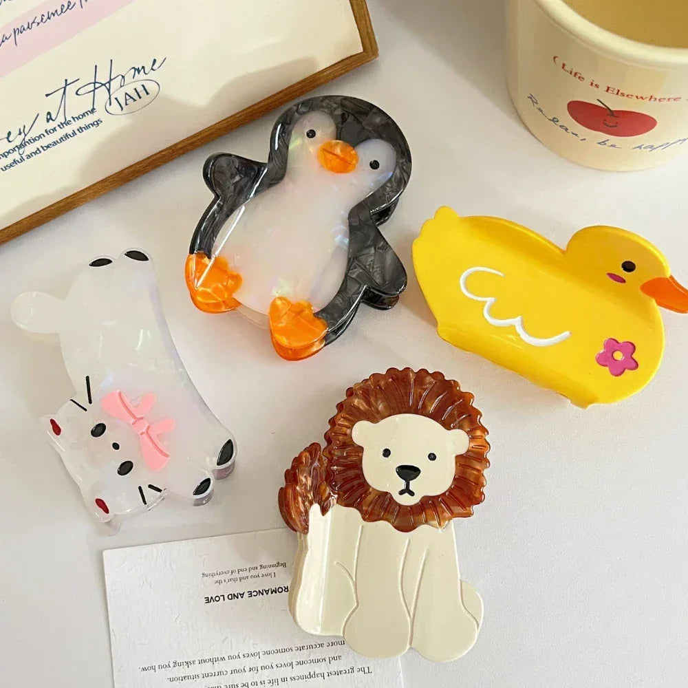 collection of animal hair claw clips including a cat, lion, penguin, and duck on a white surface