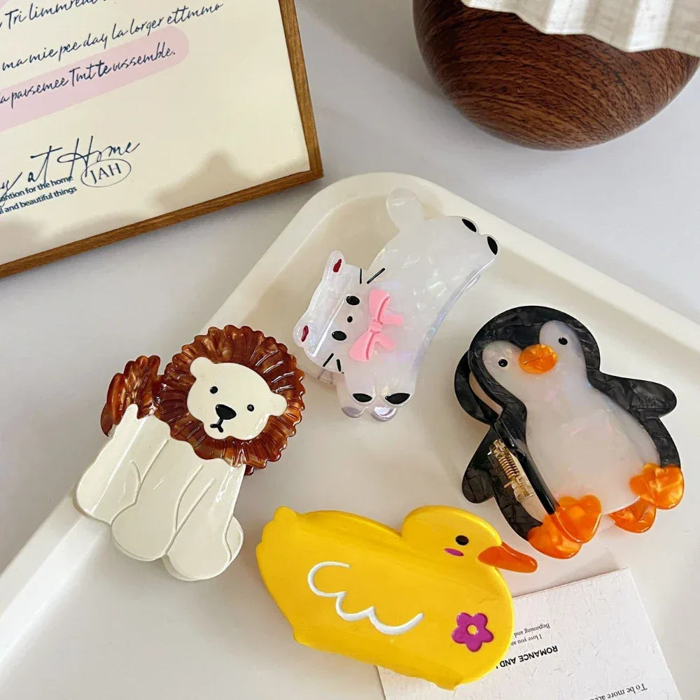 collection of animal hair claw clips including a cat, lion, penguin, and duck on a white tray