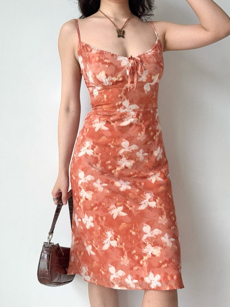 Close-up of a woman's torso wearing a floral print midi slip dress.