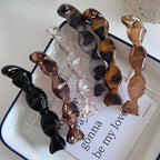 a group of candy-shaped hair clips in various colors including black, clear, brown, and marbled patterns arranged in a line