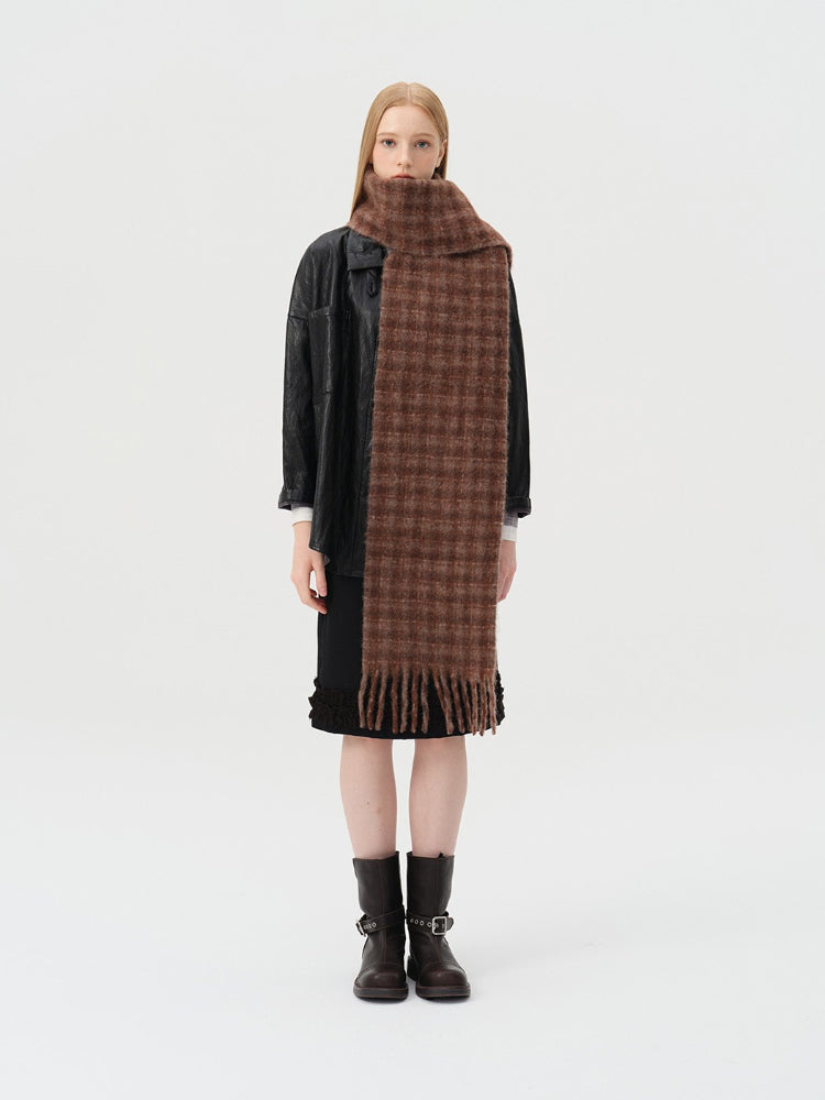 Woman wearing a brown plaid scarf, black leather jacket, and black skirt.
