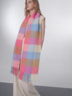 Woman modeling an oversized plaid scarf with fringe, draped around her neck.