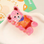 Pink iridescent bear-shaped hair claw clip with a detailed outfit, shown from a side angle