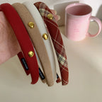 Hand holding a collection of padded headbands in red, beige, white, and plaid