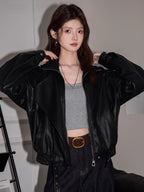 Close-up of a woman wearing a black faux leather jacket, showing the lapel collar and zipper detail.