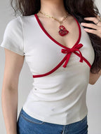 Close-up of a white ribbed knit top with red trim and a red bow.