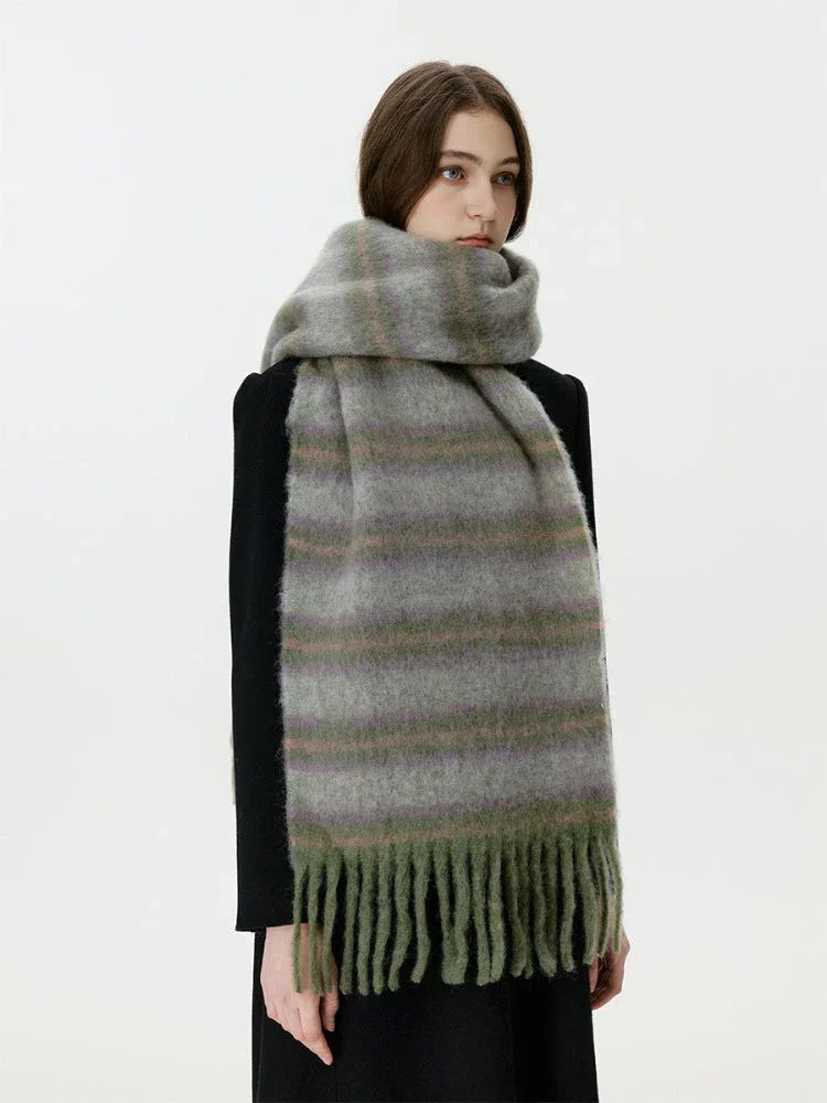 Front view of a woman wearing a black coat and a fuzzy, striped scarf with fringe detail.