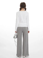 Back view of a woman wearing a white long-sleeve shirt and grey wide-leg sweatpants.