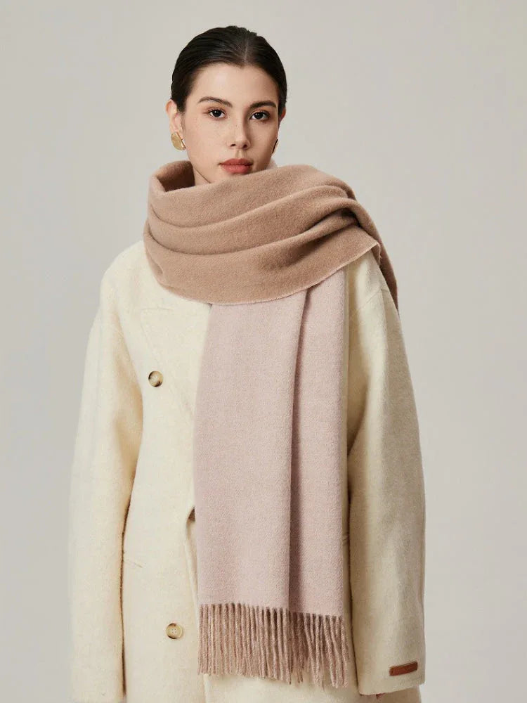 Woman wearing a cream coat and a two-toned beige and pink scarf with fringe