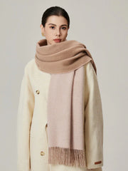 Woman wearing a cream coat and a two-toned beige and pink scarf with fringe