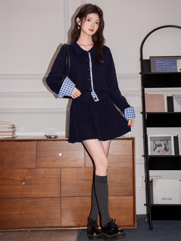 Woman in a navy blue knit cardigan and skirt set, accessorized with a black handbag and knee-high socks.