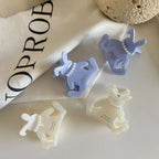 A close-up of four bunny-shaped hair claw clips in white and light purple, showcasing their design.