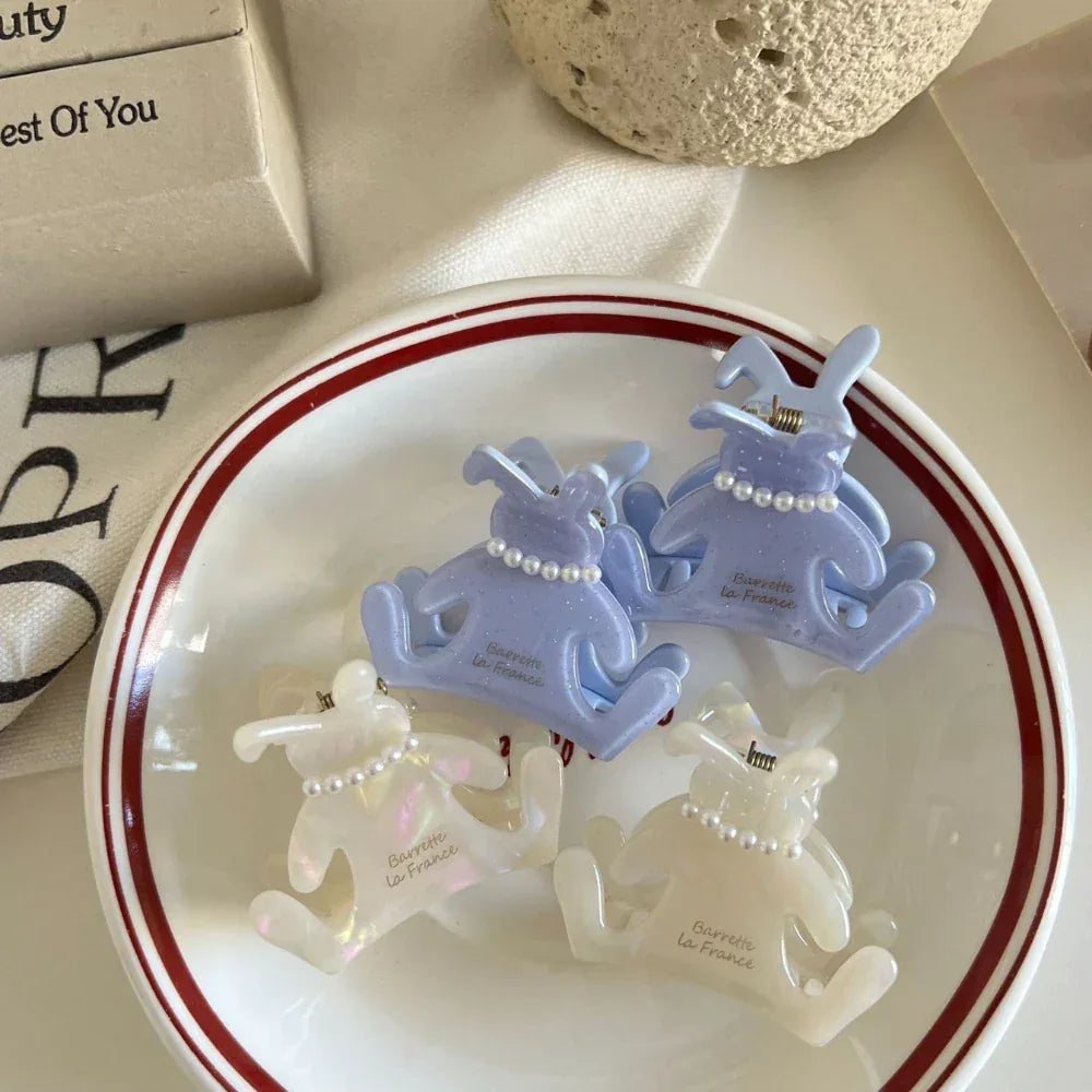 Four bunny-shaped hair claw clips in white and light purple, placed inside a white bowl with red trim.
