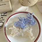 Four bunny-shaped hair claw clips in white and light purple, placed inside a white bowl with red trim.