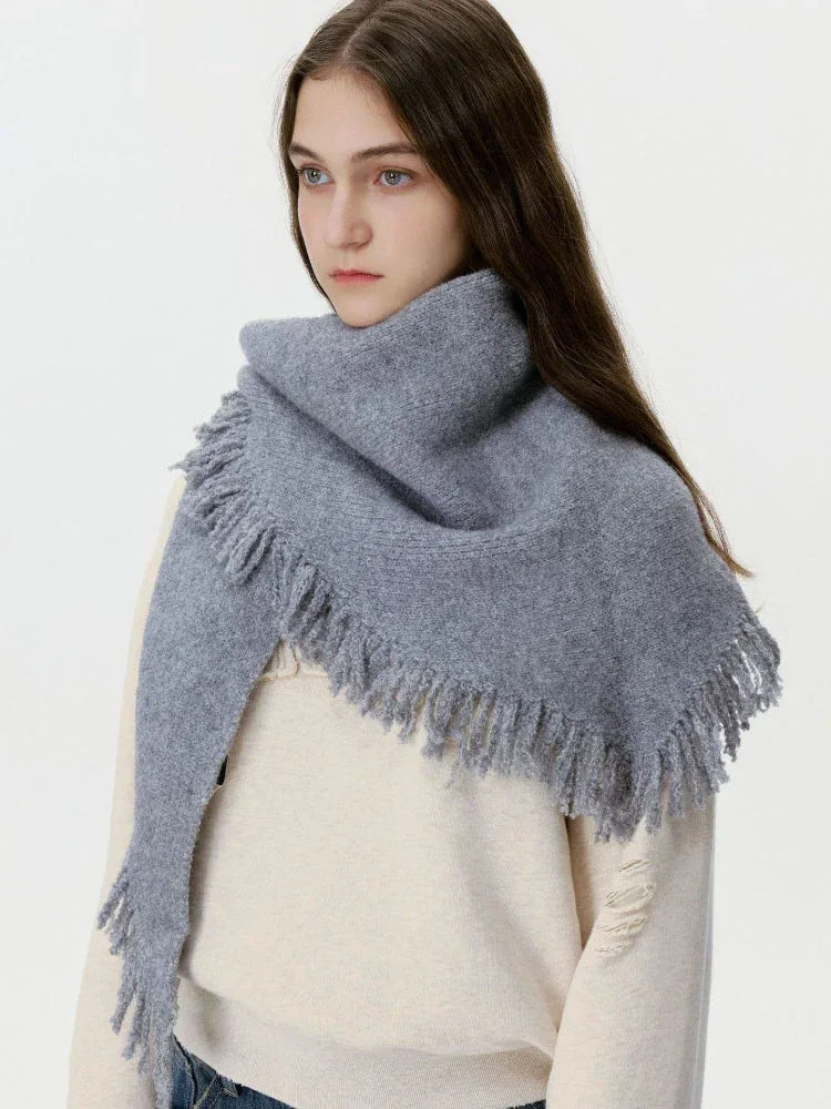 Model wearing a grey oversized scarf with fringe detail over a cream sweater