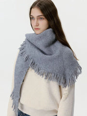 Model wearing a grey oversized scarf with fringe detail over a cream sweater