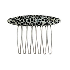 A black and white animal print hair comb with an oval decorative top and silver metal teeth, isolated on a white background.