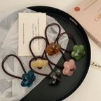 A black tray displaying a collection of flower-shaped hair ties in different colors.