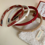 Assortment of padded headbands in red, beige, white, and plaid on a table