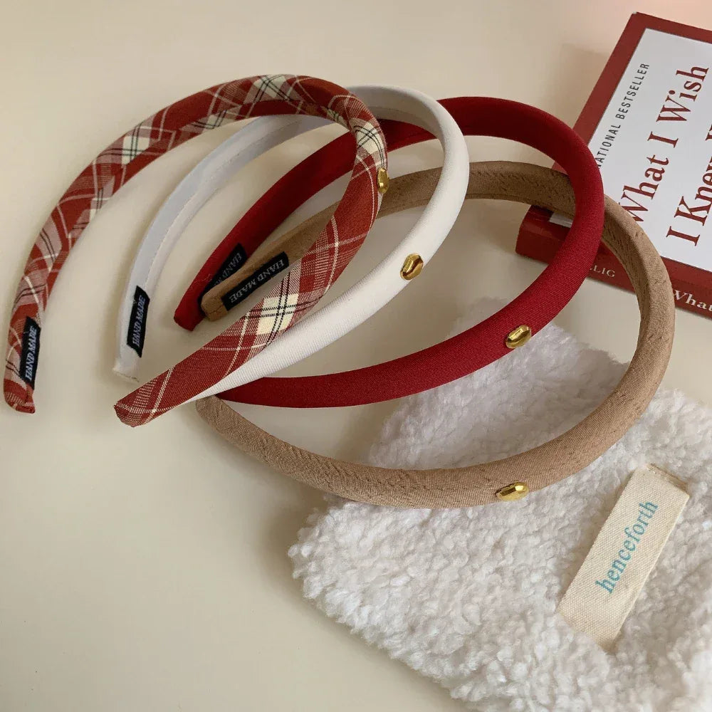 Assortment of padded headbands in red, beige, white, and plaid on a table