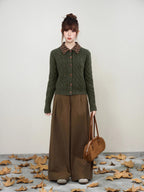 Full body shot of a woman wearing a green cable knit cardigan and brown wide-leg pants