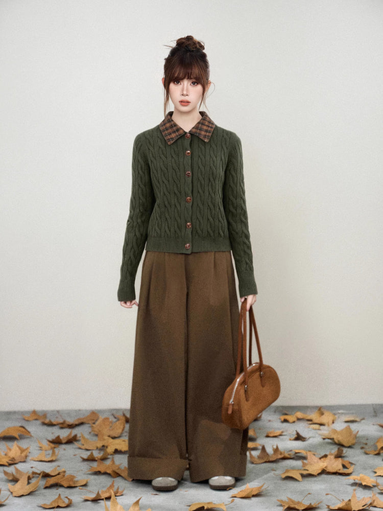 Full body shot of a woman wearing a green cable knit cardigan and brown wide-leg pants