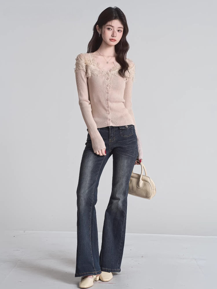 Full body shot of a woman wearing a beige ribbed knit cardigan with lace trim and a v-neck, paired with dark wash flared jeans and holding a beige handbag.
