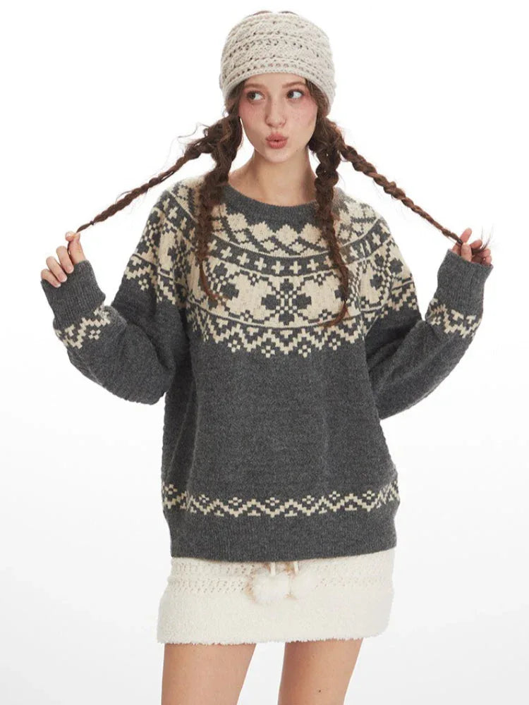 Woman wearing a grey and cream Fair Isle knit sweater and a white headband, playfully holding her braids, front view