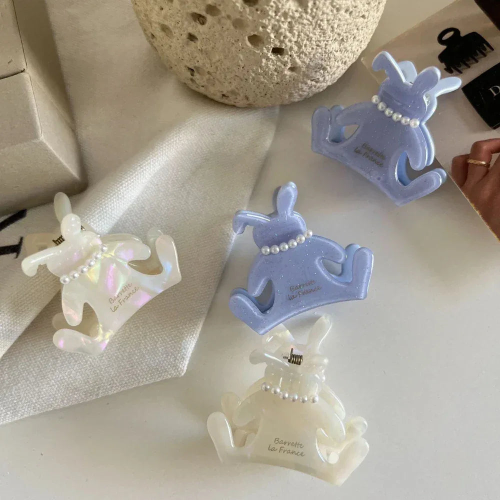 A collection of bunny-shaped hair claw clips in white and light purple, displayed on a white surface.