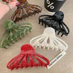 hand holding a brown octopus claw hair clip with other clips in background