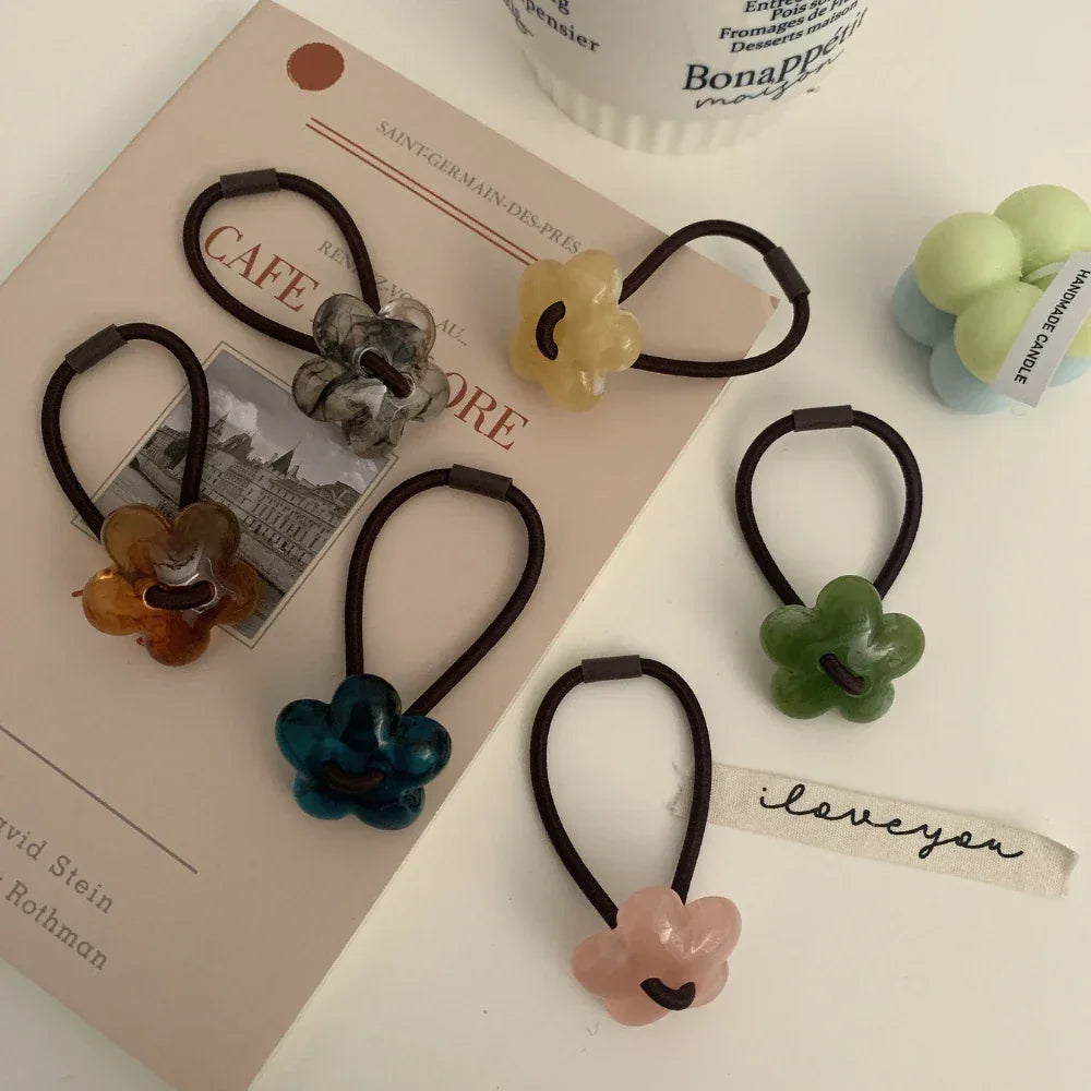 A flat lay of flower-shaped hair ties arranged around a book and a candle.