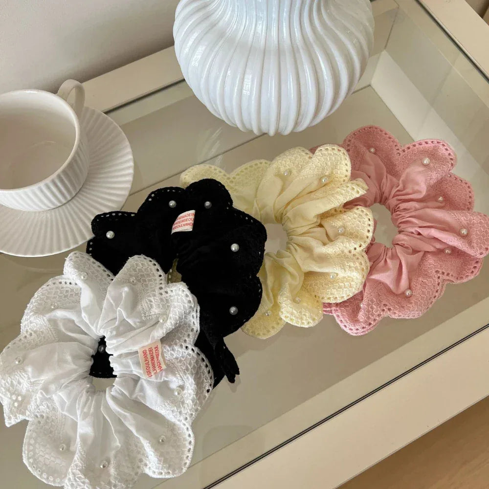 Assortment of scrunchies in white, black, yellow, and pink displayed on a glass table