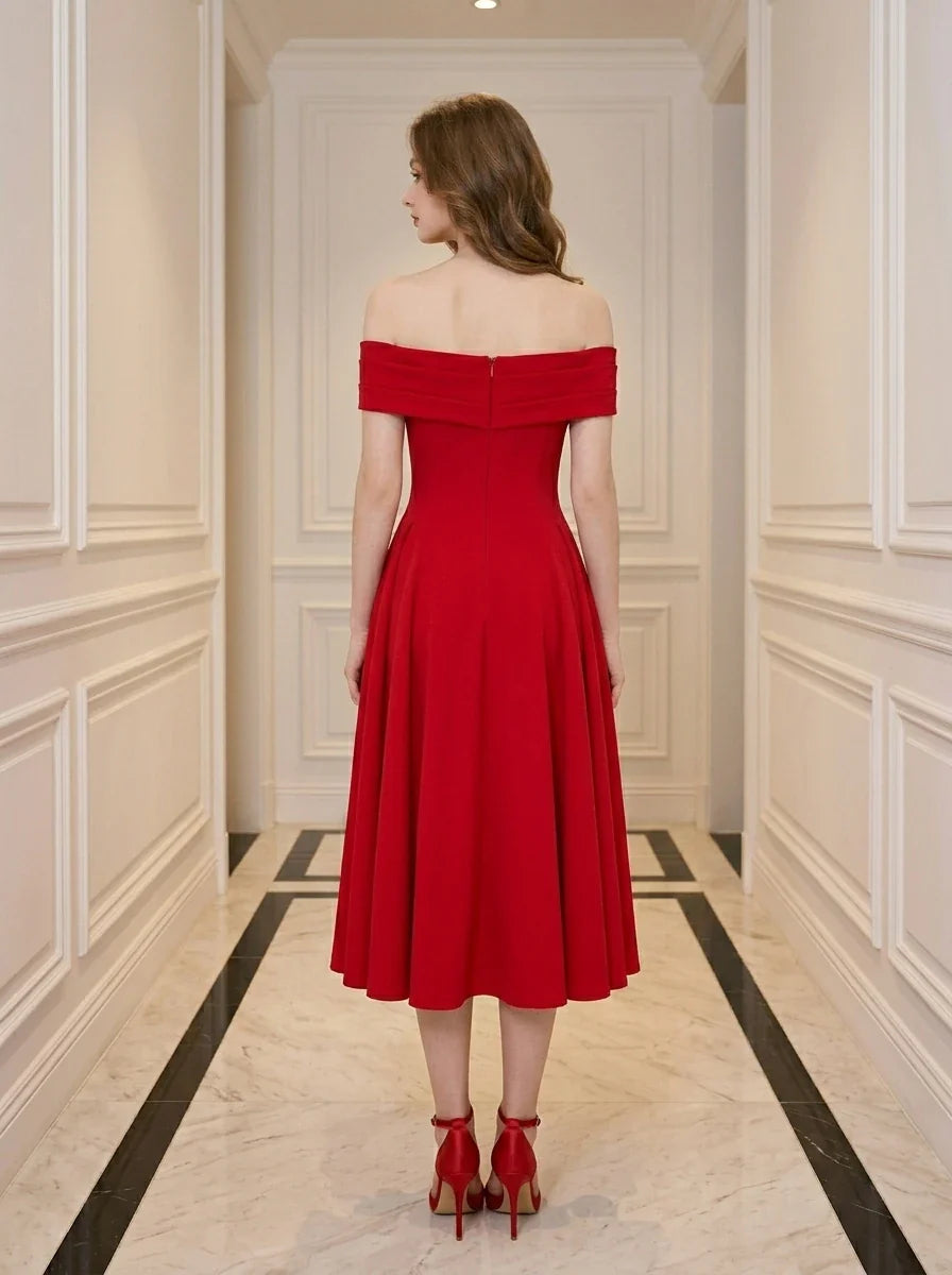 Back view of a woman wearing a red off-the-shoulder midi dress with flared skirt and red heels, standing in a hallway.