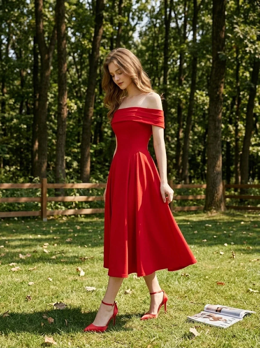 Woman wearing a red off-the-shoulder midi dress with flared skirt and red heels, walking in a grassy area with trees.