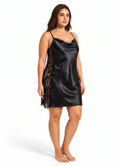 Plus size model wearing a black satin slip dress with lace side panels from the side.