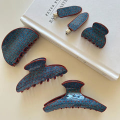 Assortment of blue polka dot hair clips with red trim arranged on a book