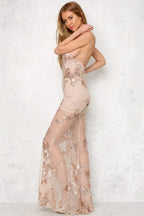 Woman in a long nude sequined and appliqued sheer dress with a high slit and deep V-neck, posing from the side