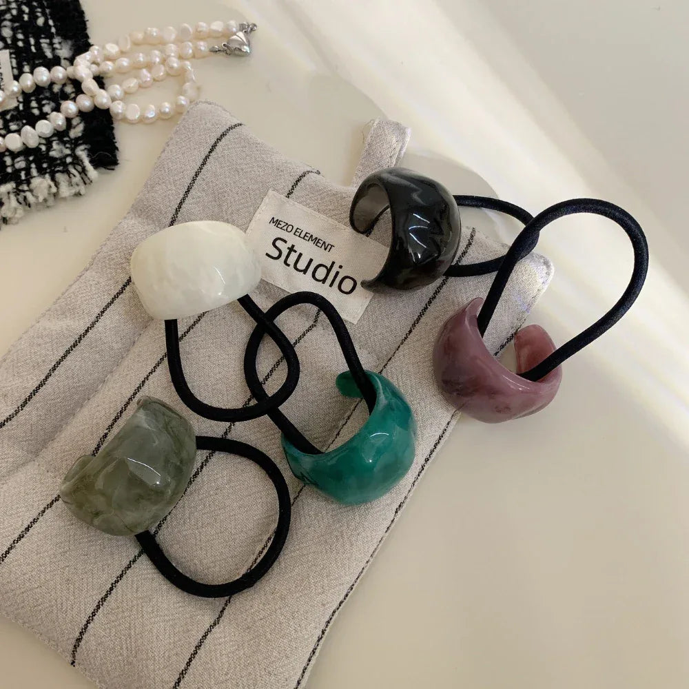 Collection of colorful resin ring hair ties on fabric