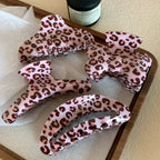 assortment of pink leopard print hair claw clips on a wooden tray