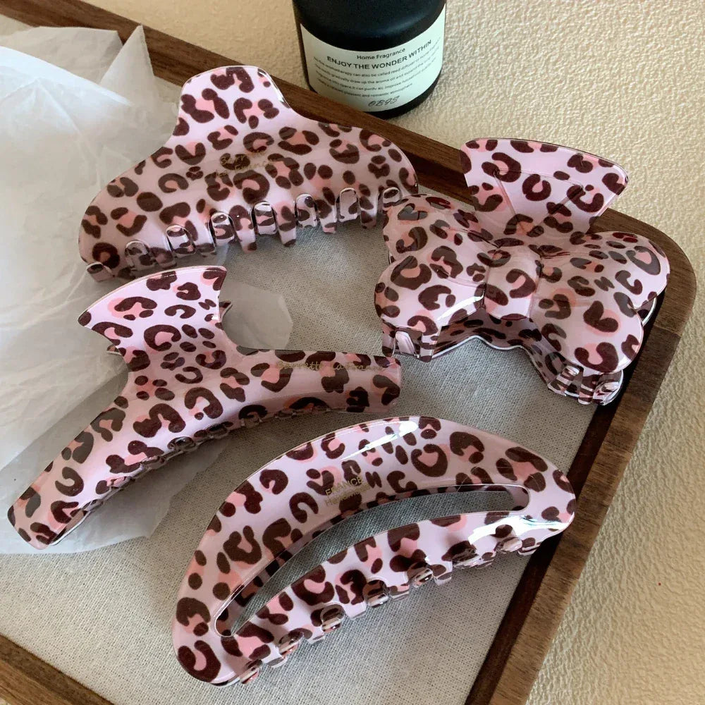 assortment of pink leopard print hair claw clips on a wooden tray