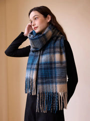 Model wearing a blue and tan plaid scarf with fringe