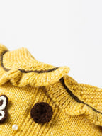 Close-up of the ruffled collar of a yellow knitted dog sweater.