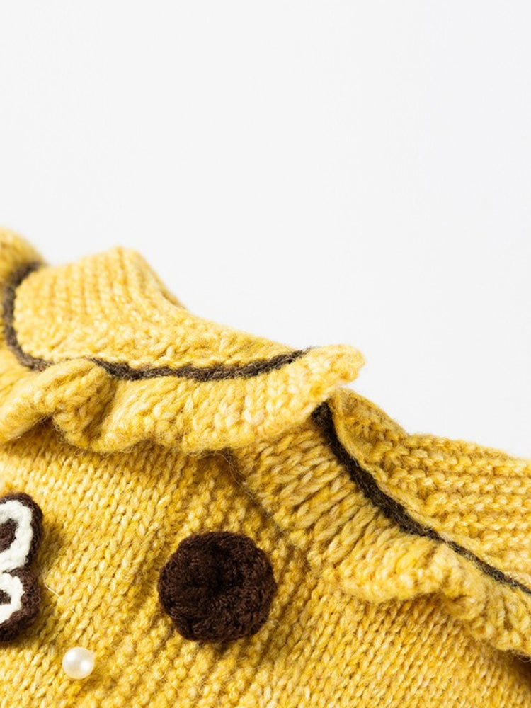 Close-up of the ruffled collar of a yellow knitted dog sweater.